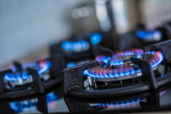 Close-up oven hobs with blue flames burning.