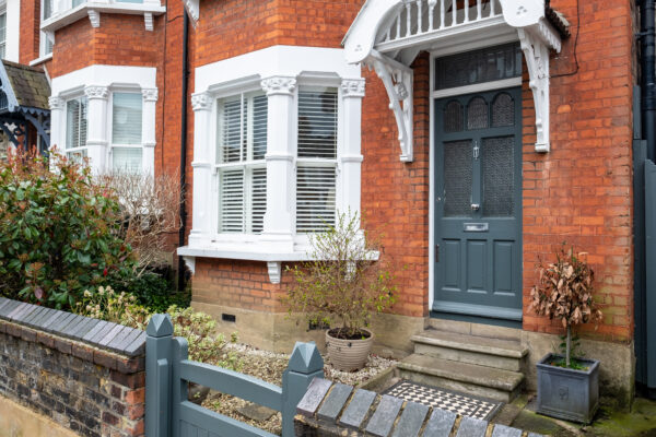 Red brick house with blue door and a small yard with blue gate