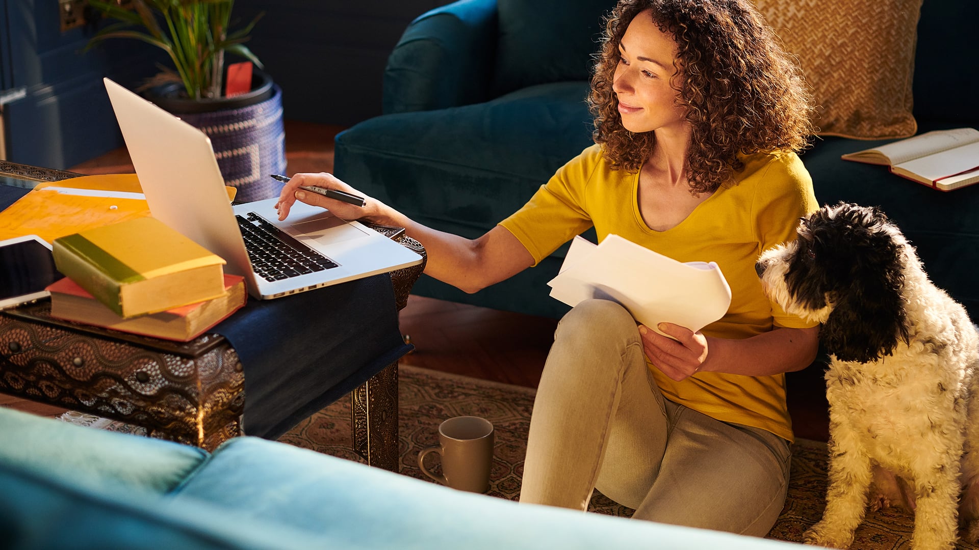 Woman on a laptop at home with a dog sitting beside her